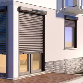 Moderne Außenansicht eines Hauses mit geschlossenen Rollläden und Terrasse bei Sonnenuntergang.