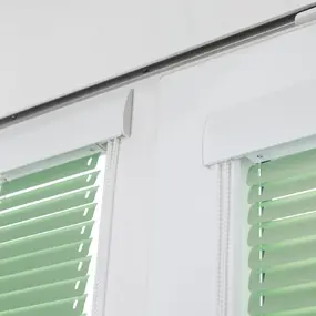 Innenaufnahme von zwei Fenstern mit modernen, grünen Jalousien und weißem Rahmen.