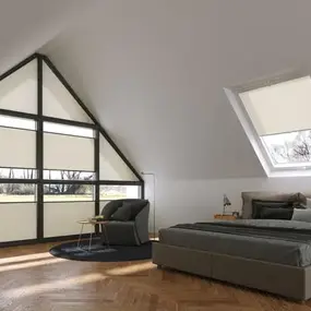 Modernes Schlafzimmer im Dachgeschoss mit großen Fenstern, Parkettboden und gemütlicher Einrichtung.