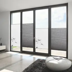 Moderne Wohnzimmer mit großen Fensterfronten und DUETTE Plissees als Sichtschutz.