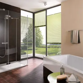 Modernes Badezimmer mit bodentiefer Dusche, Badewanne und großen Fenstern mit Plissees.