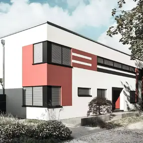 Modernes Einfamilienhaus mit Flachdach, großen Fenstern und rotem Fassadenelement.